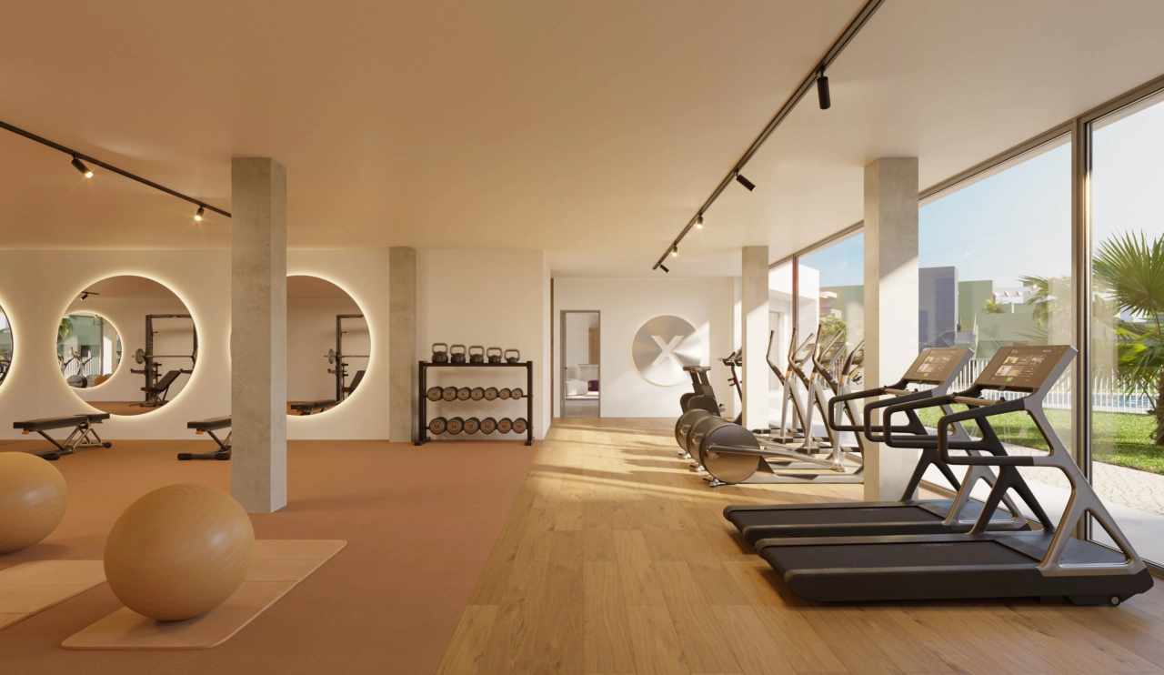 Ein voll ausgestatteter Fitnessraum mit großen Fenstern mit Blick auf die Gärten und den Poolbereich.