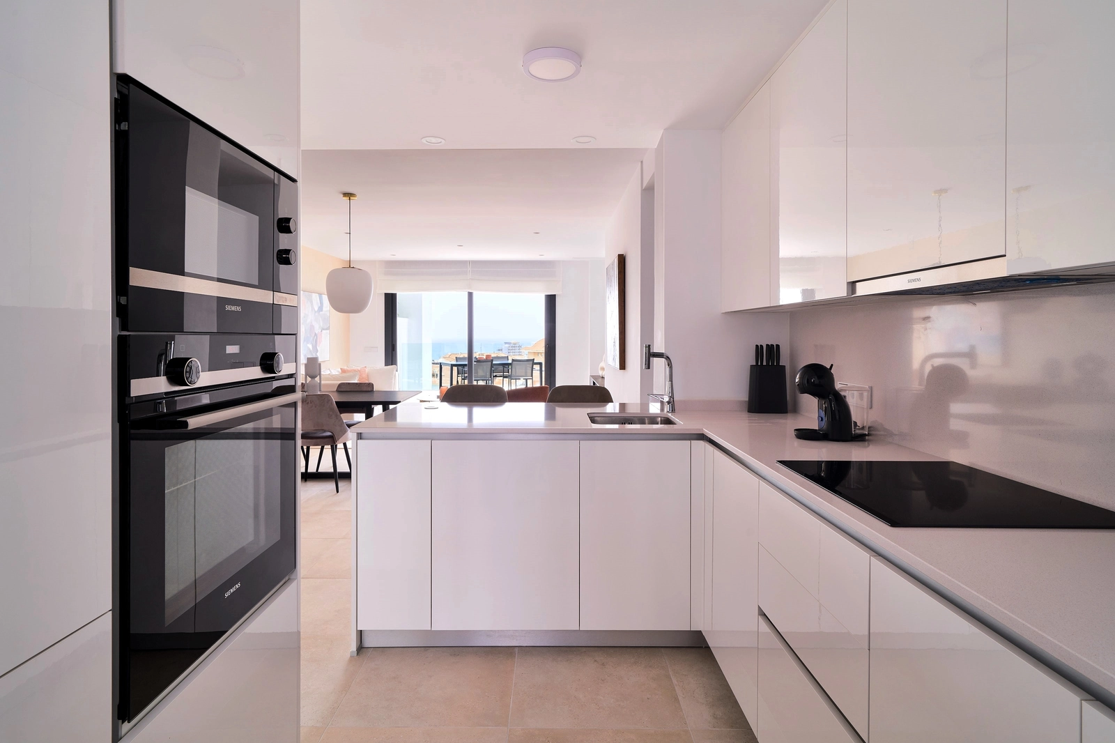 Eine moderne, voll ausgestattete Küche mit Frühstücksbar, funktional und stilvoll gestaltet, die in den Wohnbereich übergeht.