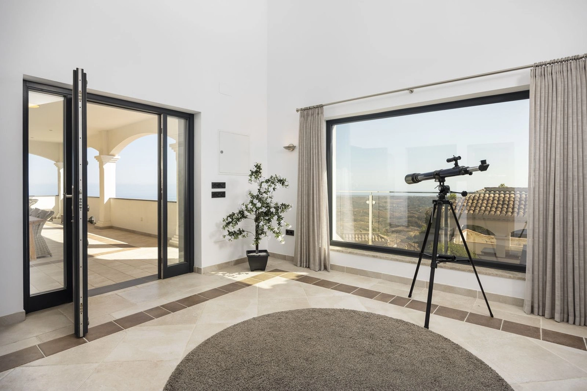 Eine ruhige Ecke des Hauses, wo große Fenster die spektakuläre Landschaft einrahmen und Türen zur Terrasse führen.
