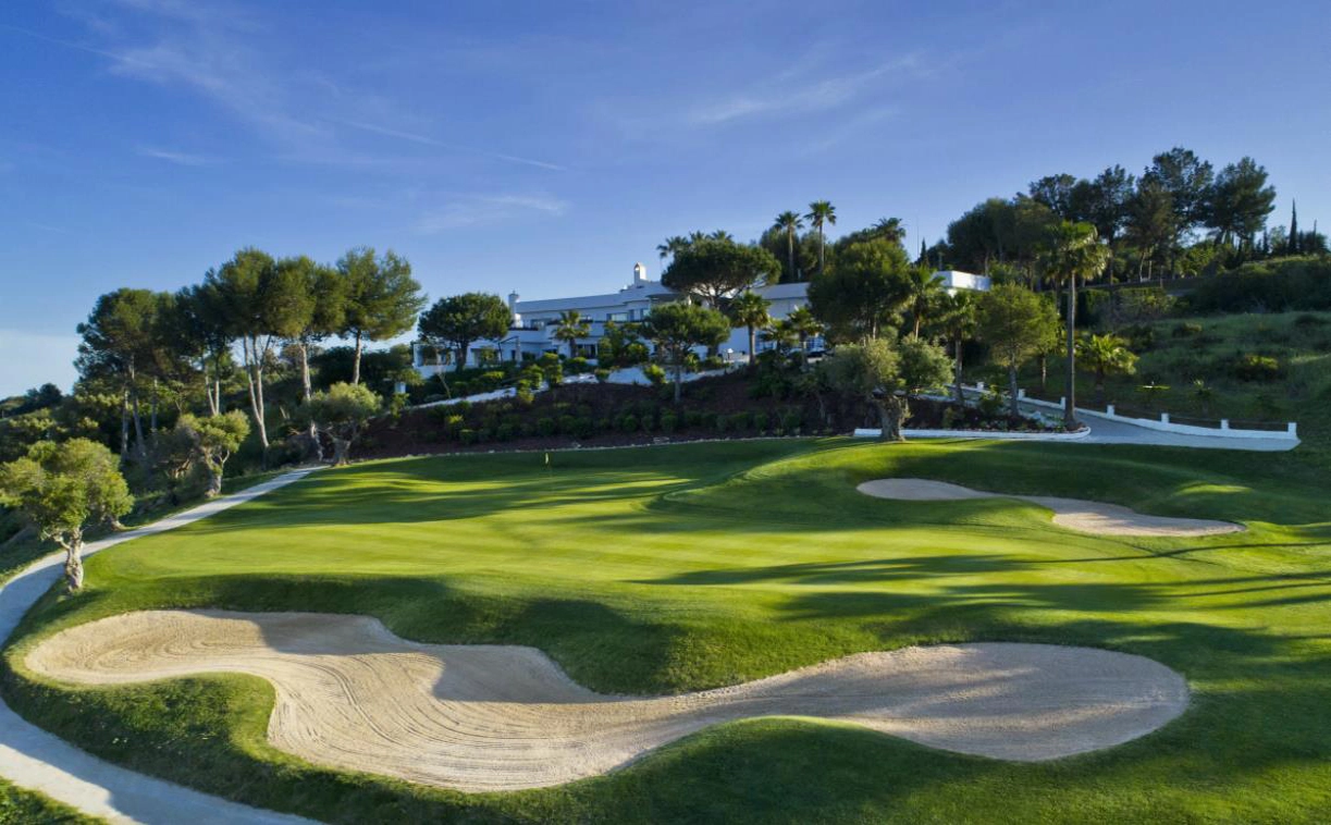 Das prestigeträchtige Clubhaus von Estepona Golf, nur einen kurzen Spaziergang von Ihrer Wohnung entfernt, vor der Kulisse gepflegter Grüns.